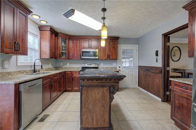 kitchen featuring stainless steel appliances, a center island, sink, and light stone counters