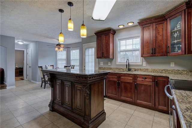 kitchen with light tile patterned flooring, pendant lighting, sink, light stone countertops, and electric stove