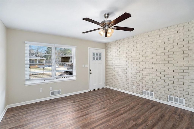 unfurnished room with ceiling fan, brick wall, and dark hardwood / wood-style floors