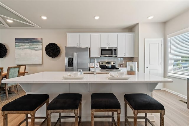 27 Cobalt Ln Unit 77, Newnan, GA 30265 - kitchen featuring stainless steel appliances, decorative backsplash, white cabinetry, a kitchen bar, and recessed lighting