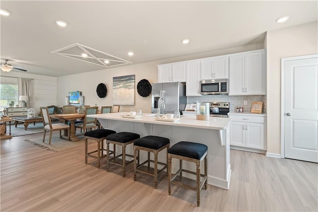 27 Cobalt Ln Unit 77, Newnan, GA 30265 - kitchen featuring appliances with stainless steel finishes, light wood finished floors, a kitchen bar, a center island with sink, and white cabinets