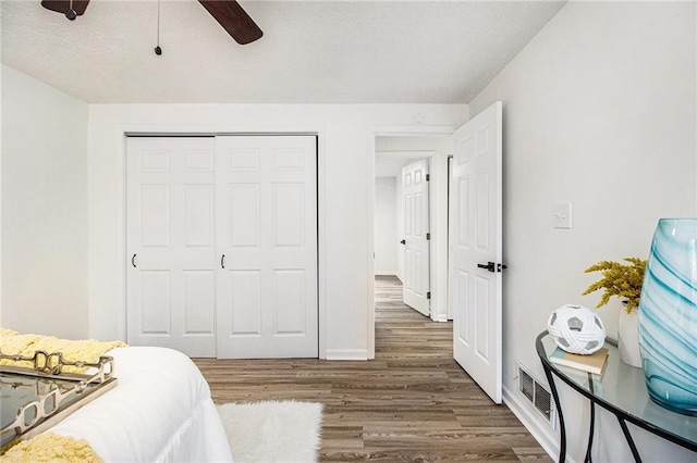 bedroom with dark hardwood / wood-style floors, ceiling fan, and a closet