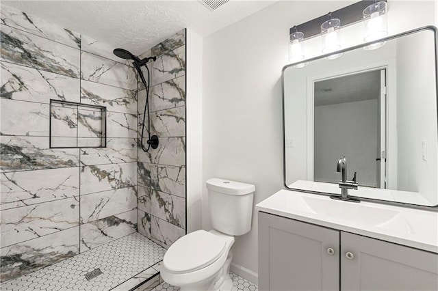 bathroom featuring tiled shower, vanity, toilet, and a textured ceiling