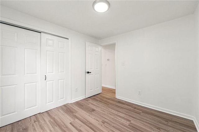 unfurnished bedroom with a closet and light wood-type flooring