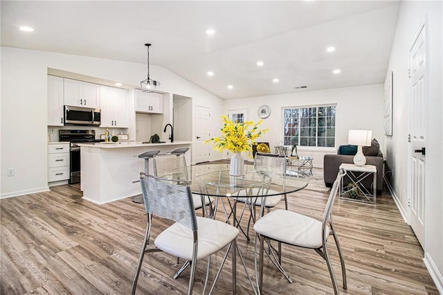 dining space featuring vaulted ceiling and light hardwood / wood-style flooring