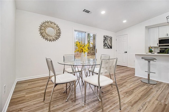 dining space featuring vaulted ceiling and light hardwood / wood-style flooring