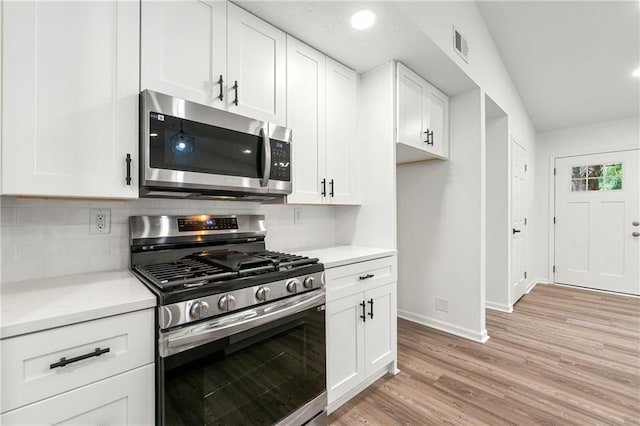 kitchen with tasteful backsplash, stainless steel appliances, white cabinets, and light wood-type flooring