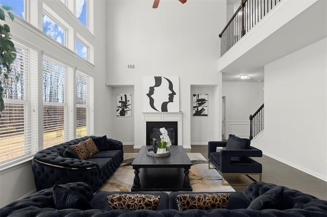 living area featuring stairway, plenty of natural light, ceiling fan, and a towering ceiling