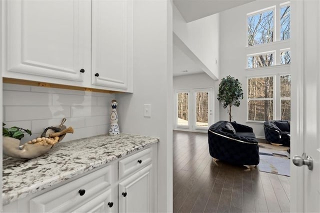 bar featuring decorative backsplash, plenty of natural light, wood finished floors, and a high ceiling