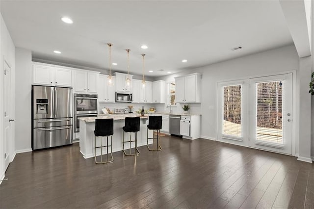 kitchen with a kitchen breakfast bar, a center island, light countertops, white cabinets, and stainless steel appliances