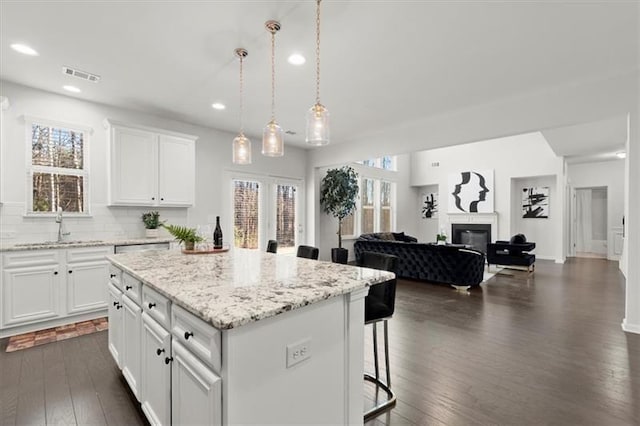 kitchen featuring a kitchen island, dark wood-style flooring, visible vents, a sink, and recessed lighting