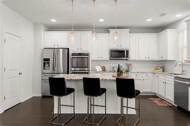 kitchen with a kitchen island, visible vents, tasteful backsplash, a sink, and stainless steel appliances