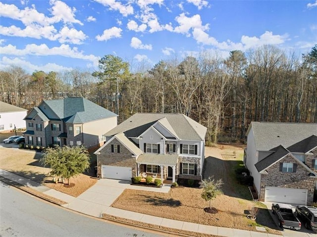 view of front of home featuring an attached garage, concrete driveway, a porch, and stone siding