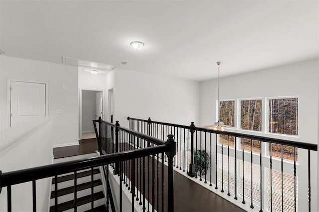 corridor featuring baseboards, attic access, and an upstairs landing
