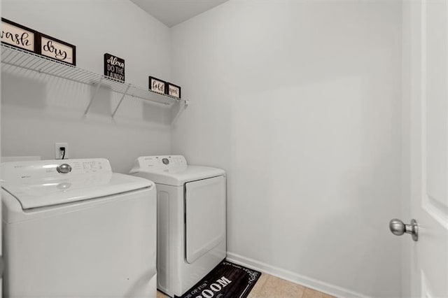 clothes washing area with laundry area, baseboards, light tile patterned floors, and washing machine and dryer