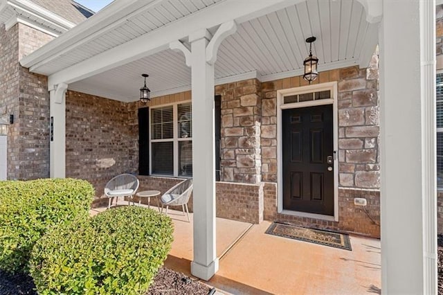 doorway to property featuring covered porch, stone siding, and brick siding