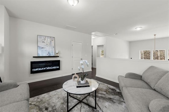 living area featuring baseboards, a fireplace, wood finished floors, and visible vents