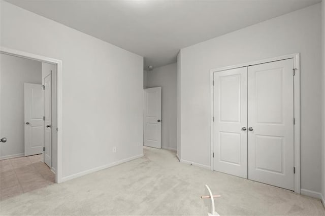 unfurnished bedroom with baseboards, carpet, and a closet