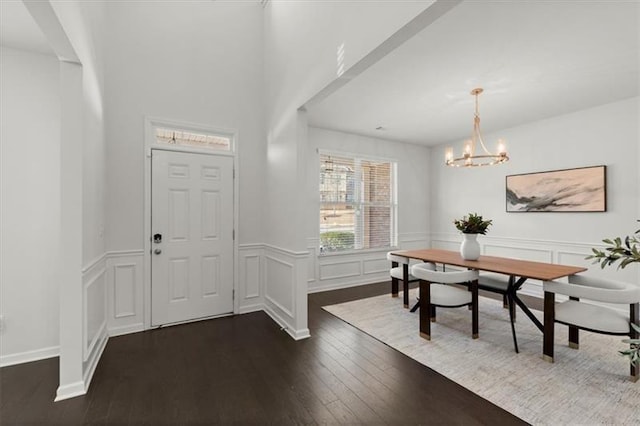 foyer featuring a notable chandelier, dark wood-style floors, and a wainscoted wall