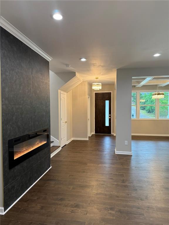 foyer entrance featuring a chandelier, coffered ceiling, baseboards, dark wood-style flooring, and ornamental molding