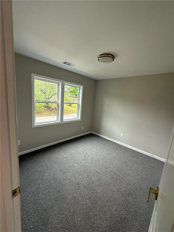 unfurnished room with dark carpet and baseboards
