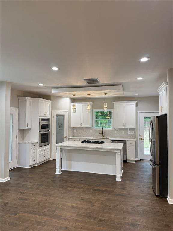 kitchen featuring stainless steel fridge, gas stovetop, a sink, white cabinetry, and recessed lighting