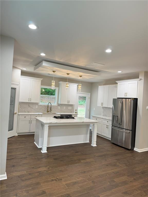 kitchen featuring double oven, dark wood-style flooring, white cabinets, and light stone countertops