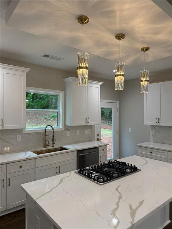 kitchen view of a sink, white cabinets, backsplash, and light stone countertops