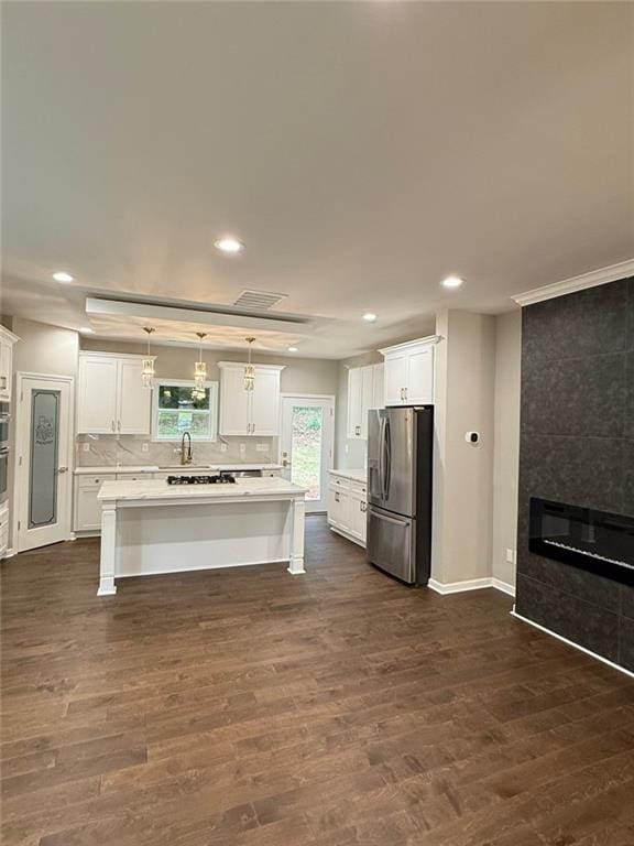 kitchen featuring stainless steel appliances, open floor plan, a large fireplace, dark wood-type flooring, and a chandelier
