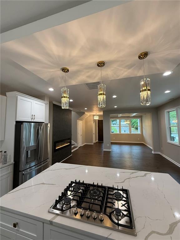 unfurnished living room featuring a chandelier, recessed lighting, a tiled fireplace, baseboards, and dark wood-style floors