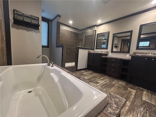 full bath with wood finished floors, double vanity, crown molding, walk in shower, and a garden tub