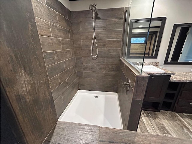 full bath featuring vanity, wood finished floors, and a tile shower