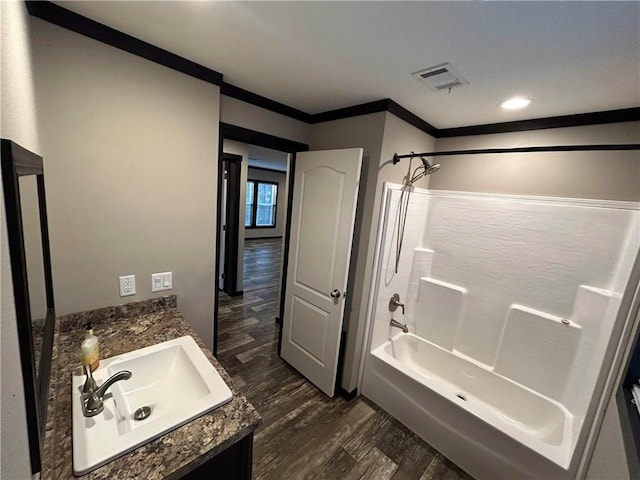 bathroom with visible vents, wood finished floors, shower / bathing tub combination, crown molding, and vanity