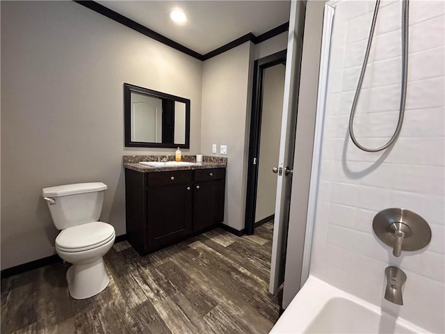 bathroom with vanity, wood finished floors, baseboards, crown molding, and toilet