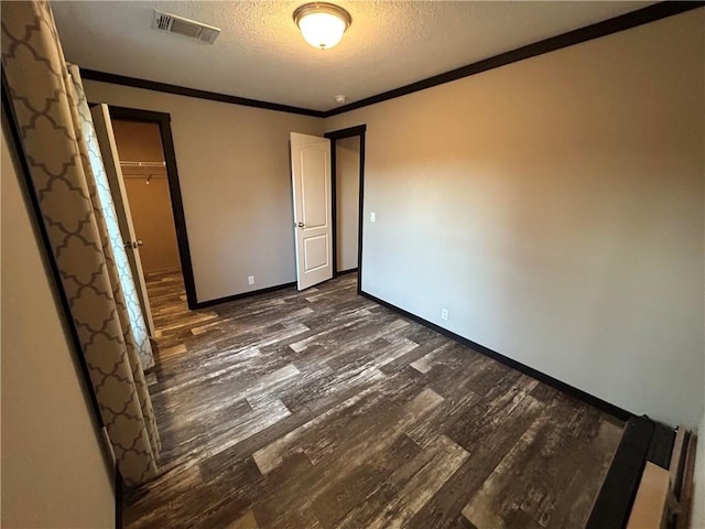 unfurnished bedroom with baseboards, ornamental molding, dark wood-type flooring, a closet, and a textured ceiling