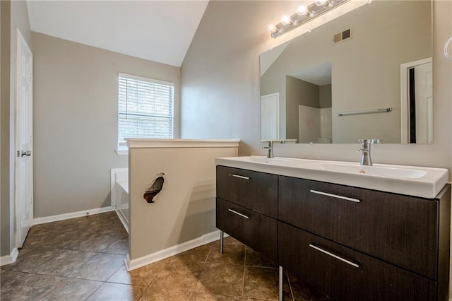 bathroom featuring tile patterned flooring, vanity, a bath, and lofted ceiling