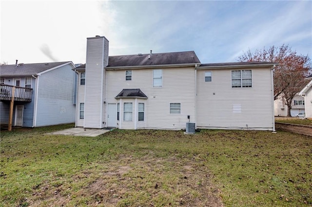 rear view of property featuring a wooden deck, a patio area, and a lawn