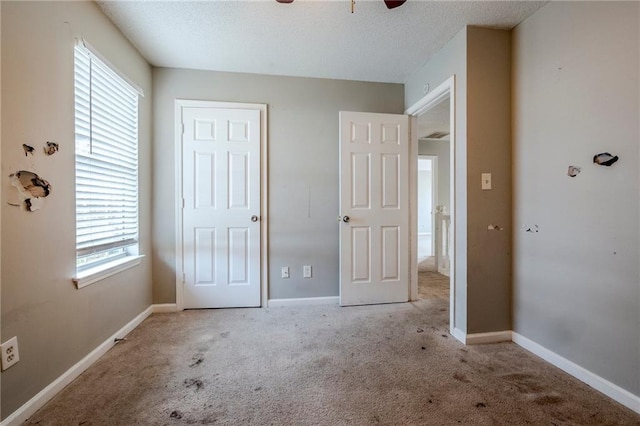 unfurnished bedroom featuring ceiling fan, light colored carpet, and a textured ceiling