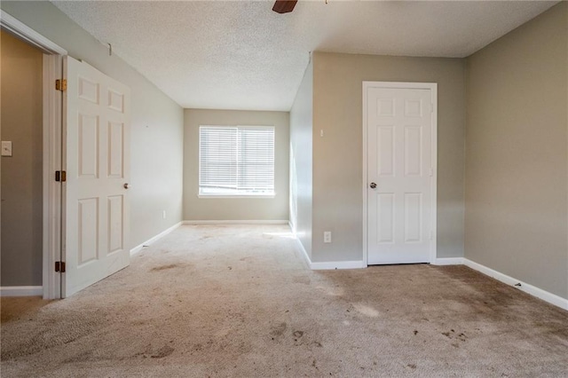 unfurnished room featuring a textured ceiling, light colored carpet, and ceiling fan