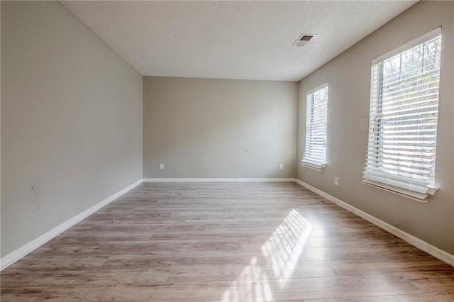 unfurnished room with a textured ceiling and light hardwood / wood-style flooring