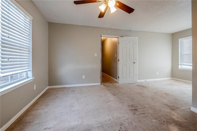 unfurnished room with ceiling fan, light colored carpet, and a textured ceiling