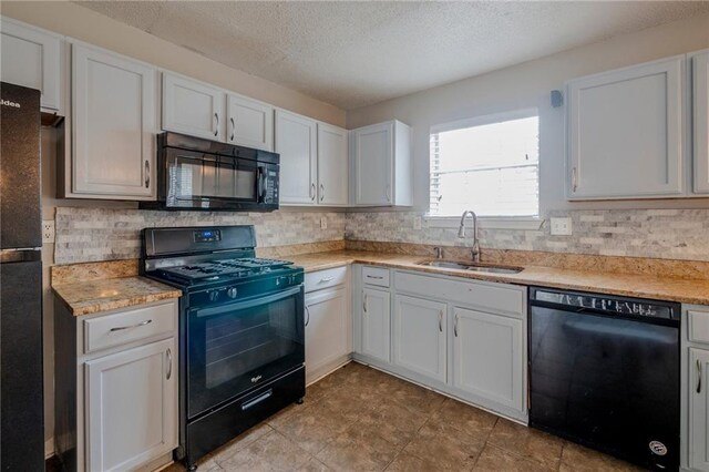 kitchen featuring tasteful backsplash, a textured ceiling, sink, black appliances, and white cabinetry