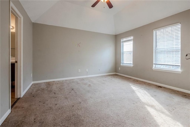 carpeted empty room with a wealth of natural light, ceiling fan, and vaulted ceiling