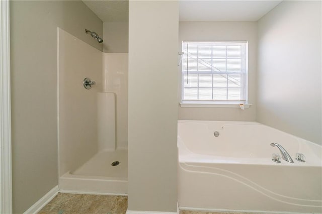 bathroom with a garden tub, baseboards, and walk in shower