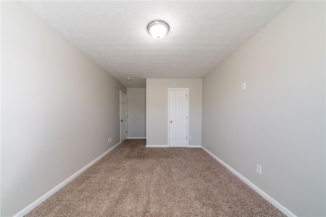 unfurnished room featuring a textured ceiling, carpet floors, and baseboards