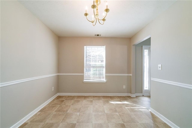 empty room with a notable chandelier, visible vents, and baseboards