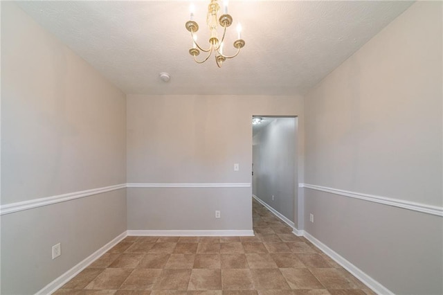 spare room with a notable chandelier and baseboards