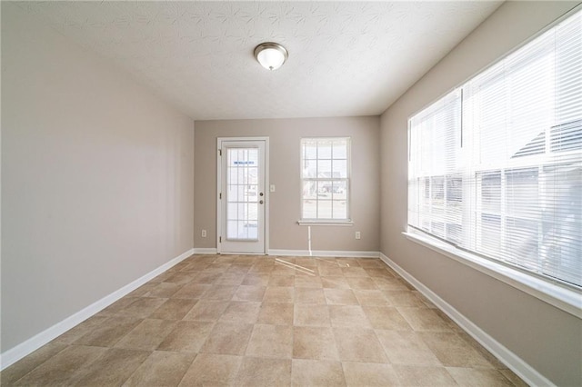 interior space featuring a textured ceiling and baseboards