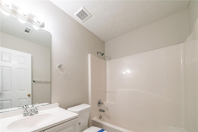 bathroom featuring visible vents, vanity, toilet, and a textured ceiling