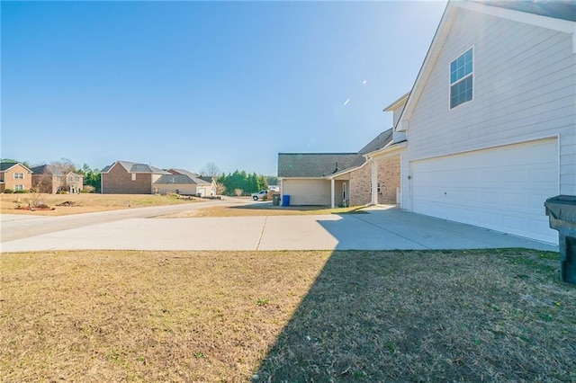 view of yard featuring driveway, an attached garage, and a residential view